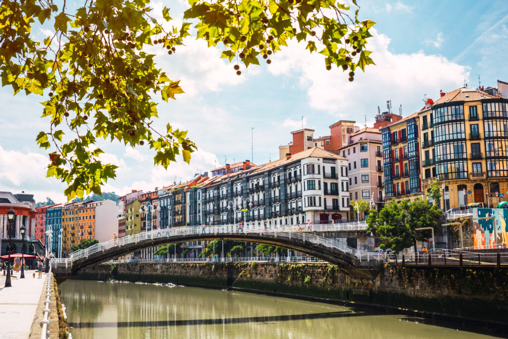 Landscape view of Bilbao downtown with the Nervion river, Ribera bridge and its colorful architecture on a sunny day.