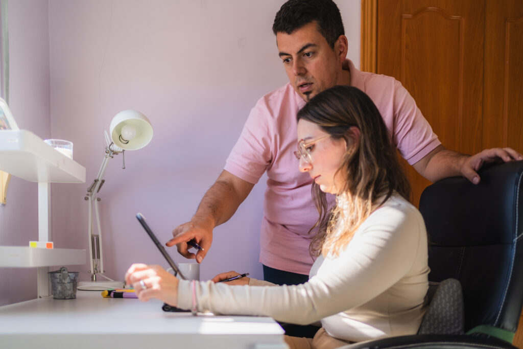 Two colleagues using a tablet and discussing work in a home office