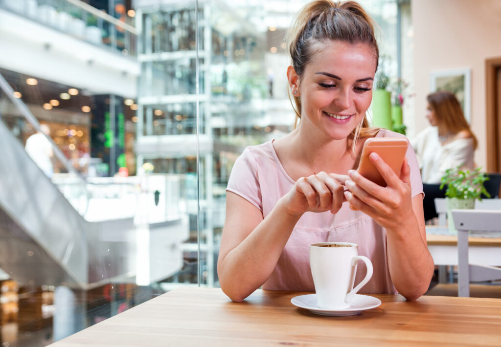 Woman using mobile phone in cafe at shopping mall.